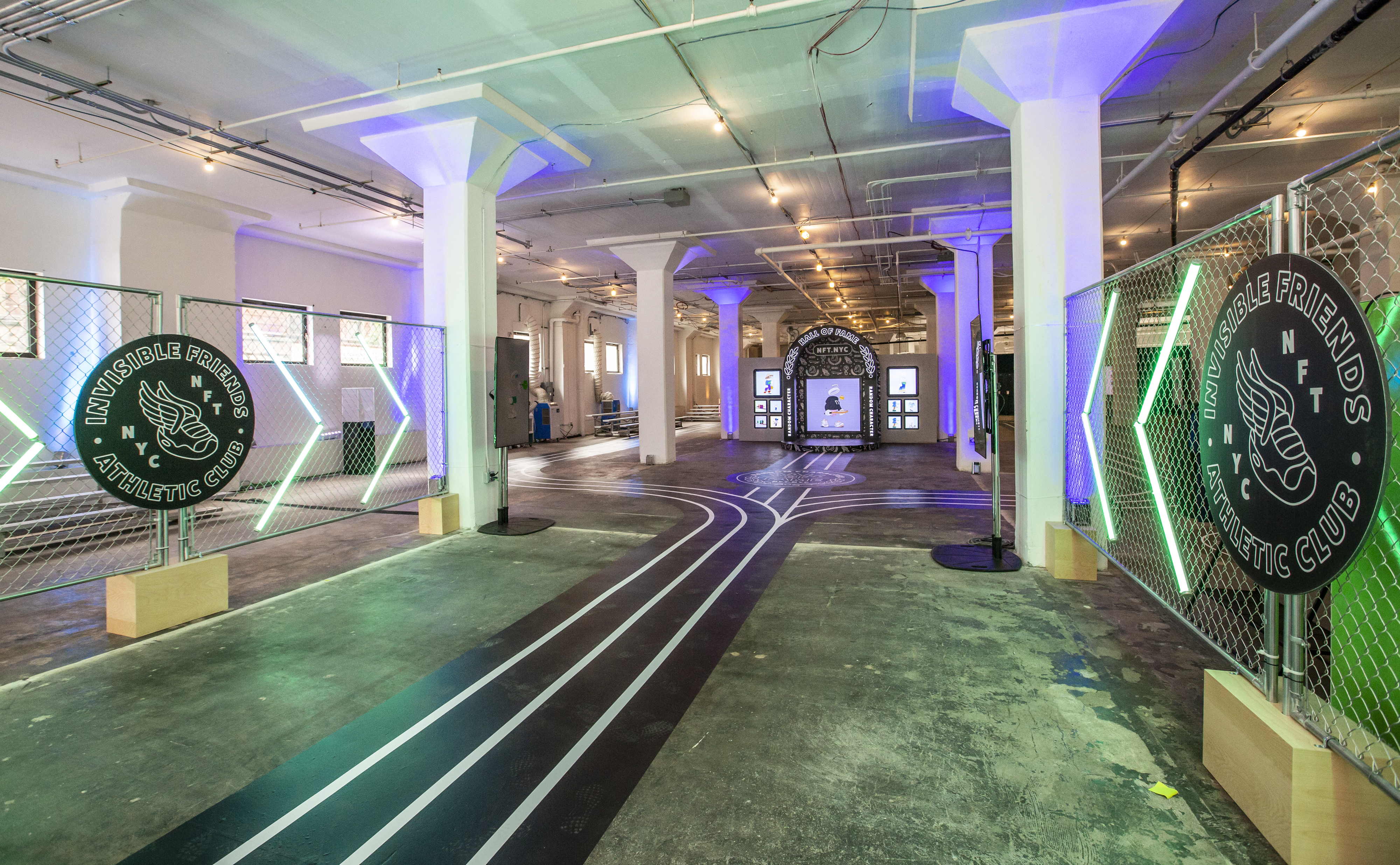 Center of the RCC x Shopify activation — Invisible Friends Athletic Club chain-link gates with neon green accents flank a painted track running toward a Hall of Fame photo moment with character displays in the back, lit in purple and green