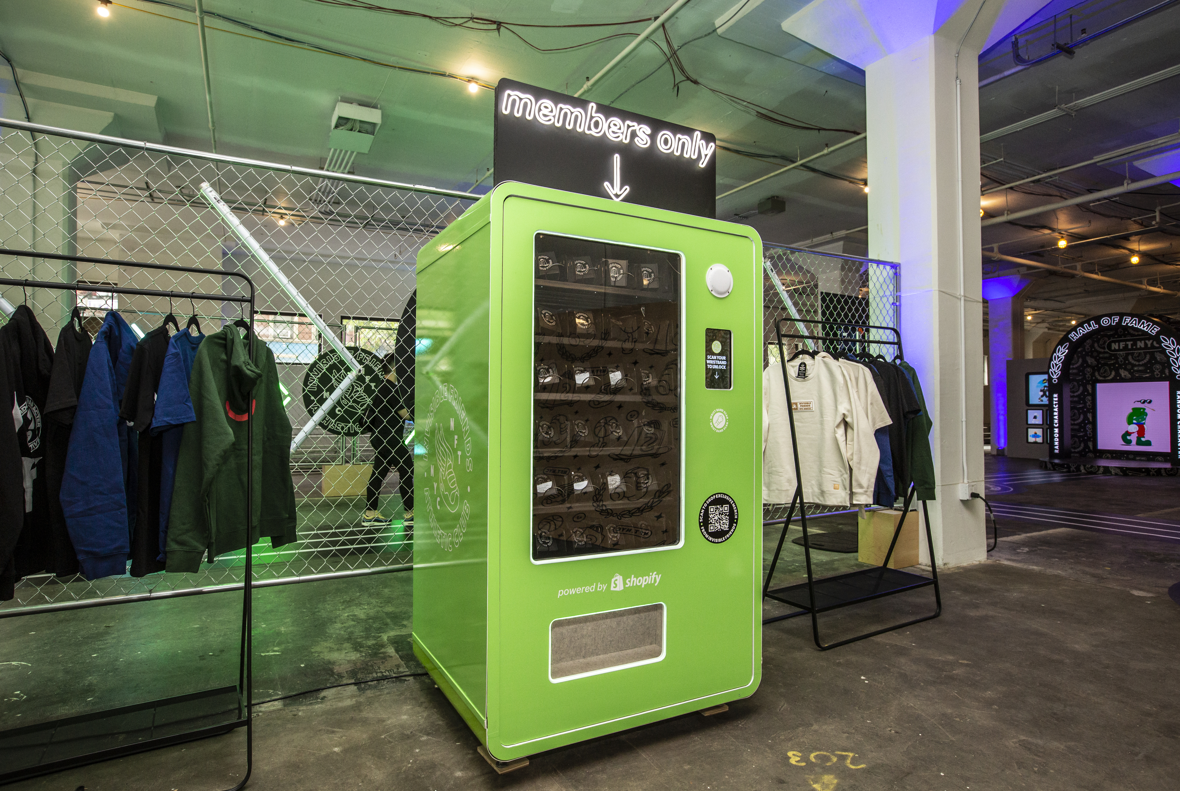 RCC x Shopify NFT.NYC installation — green members-only vending machine powered by Shopify surrounded by apparel racks