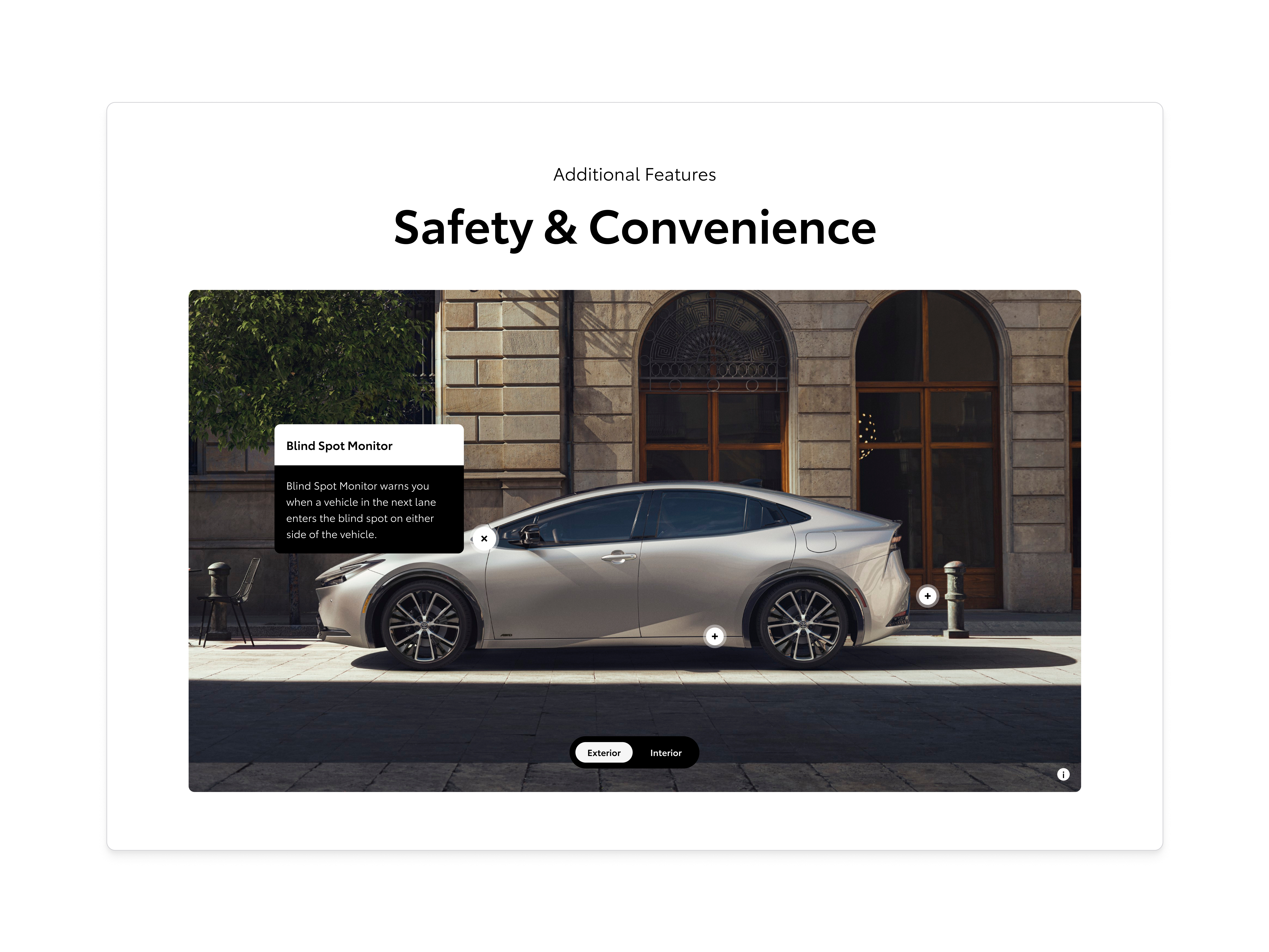 Additional Features Safety & Convenience hub showing a silver Toyota Prius parked on a sunlit cobblestone street in front of arched stone facades, with a Blind Spot Monitor callout describing how the system warns of vehicles in the next lane, plus-sign hotspots over the wheels, and an Exterior / Interior pill toggle at the bottom.